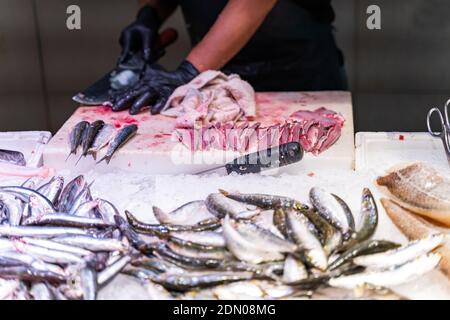 Seller cleans and chops fish at a fish market in Barcelona Foto Stock