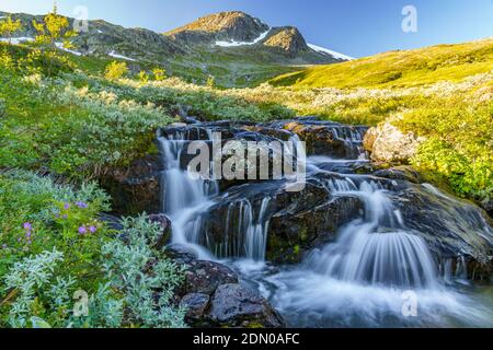 Waterfall with mountains in background with snow on them, evening light with blue sky, Gällivare county, Stora sjöfallet nationalpark, Swedish Lapland Stock Photo