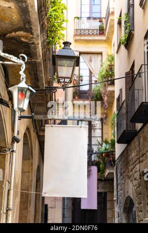 Strada stretta con vecchie case storiche e cartelloni bianchi vuoti A Barcellona Foto Stock