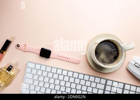 Tavolo da ufficio con vista piatta o dall'alto. Spazio di lavoro vuoto, tastiera, penna, pianta verde succulenta e tazza da caffè su sfondo rosa. Foto Stock
