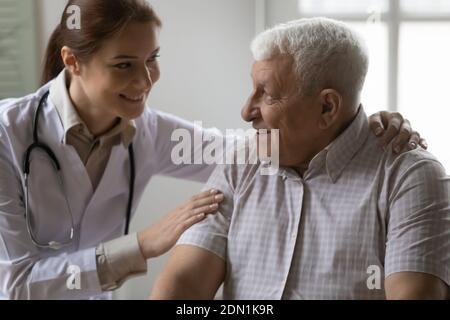 Il supporto medico femminile amichevole incoraggia il paziente maschio maturo con capelli grigi Foto Stock