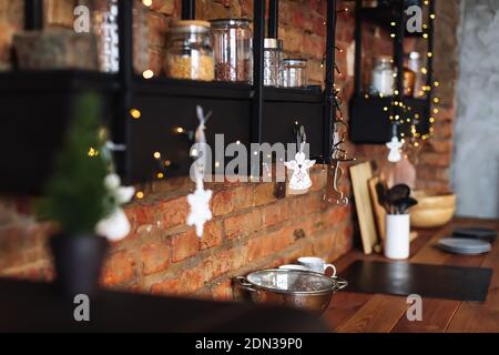 Vista su un'accogliente cucina arredata con mobili in legno. Elegante loft interno dello studio con molte luci. Concetto di preparazione della vigilia di Natale e di New Yea Foto Stock