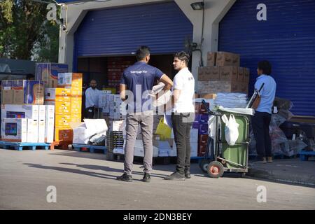 Lavoratori con carrelli elevatori manuali e scatole stoccaggio merci vicino magazzino in negozio all'ingrosso. Retro del supermercato. Banchina di scarico merci a stor Foto Stock