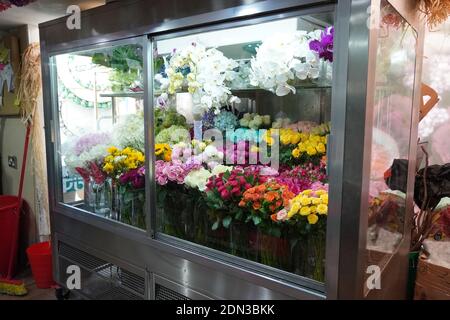 Varietà di fiori in vendita in una speciale sala fredda con aria condizionata. Frigorifero per fiori. Davanti al frigorifero con bouquet di fiori come la rosa Foto Stock