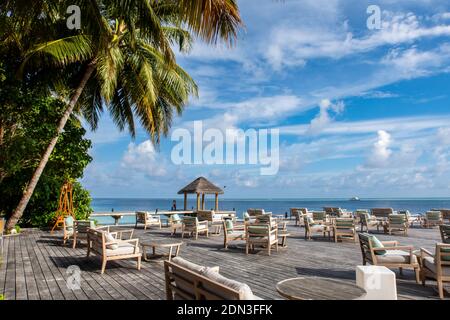 Piattaforma di legno che si affaccia sull'oceano con tavoli e divani, ristorante in un resort di lusso, paradiso tropicale, Maldive. Foto Stock