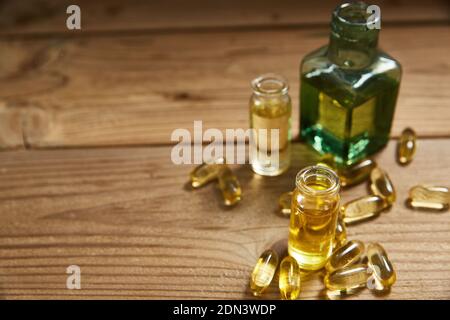Le capsule e le bottiglie di olio di pesce Omega 3 giacciono su un tavolo di legno. Foto Stock