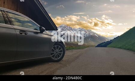 Un'auto parcheggiata sul lato di una strada in Alpi italiane Foto Stock