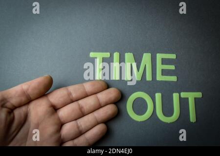 Mano umana che mostra la parola Time out scritto con lettere di plastica su sfondo di carta grigio scuro, concetto Foto Stock