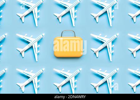 Motivo geometrico realizzato con aereo e valigia su sfondo blu.Vacanze e concetto di viaggio Foto Stock