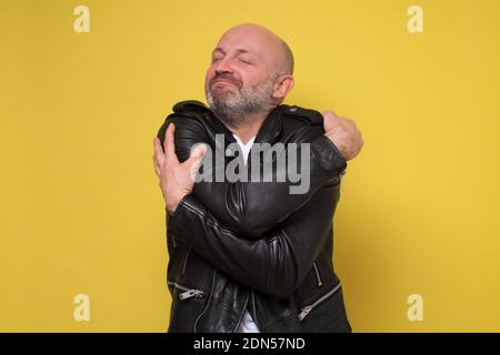 Uomo ispanico maturo che si agguonava. Studio girato su parete gialla. Foto Stock