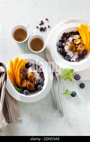 Dolce colazione caraibica di porridge di riso nero con latte di cocco e mango, banane fritte. Sana cucina giamaicana. E caffè Foto Stock