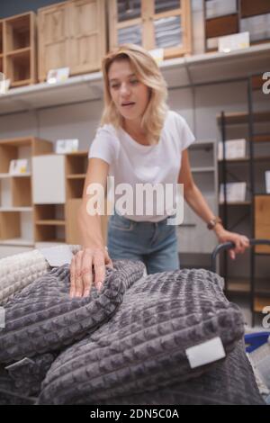 Fuoco selettivo sui cuscini morbidi casalinga matura sta comprando a. negozio di mobili Foto Stock