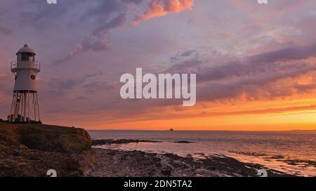 Un'immagine al tramonto con il faro di Black Nore che si affaccia sul canale di Bristol sulla costa vicino Portishead, Somerset, Inghilterra, Regno Unito. Foto Stock