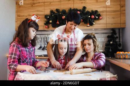 La nonna insegna ai suoi figli e nipoti a cucinare biscotti secondo una vecchia ricetta. Foto Stock