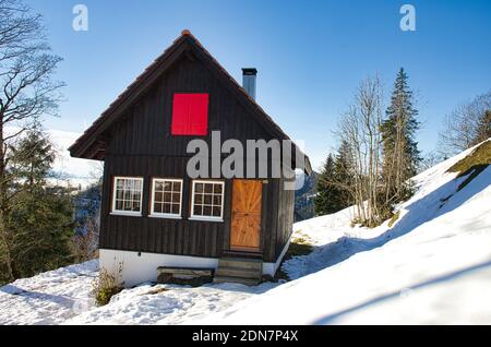 rifugio in un paesaggio invernale, vista di un rifugio in inverno, foto di zurigo oberland svizzera, paesaggio collinare, capanna con otturatore rosso Foto Stock