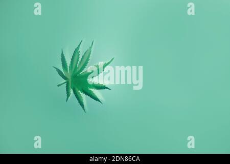 Una foglia di cannabis sfocata su sfondo verde. Spazio di copia. Foto Stock