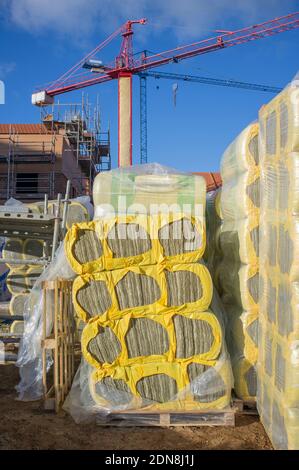 Glass wool packs at construction site. Cranes at bottom Stock Photo