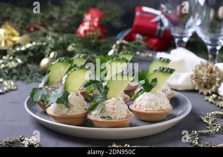 Tartine con bastoncini di granchio, formaggio cremoso e cetriolo su un piatto su sfondo grigio. Spuntino festivo di Capodanno. Primo piano Foto Stock