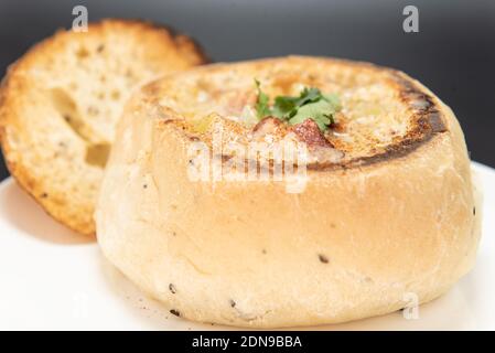 Ciotola di zuppa di vongole abbondante contenuta in una ciotola per il pane al forno. Foto Stock