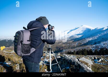 Uomo in montagna fotografando la montagna coperta di neve Foto Stock