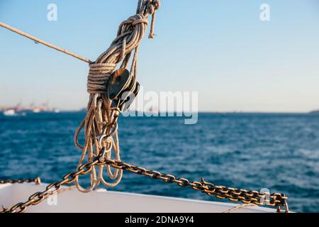 Una corda legata ad un peso su una barca fissata alla ringhiera metallica, primo piano Foto Stock