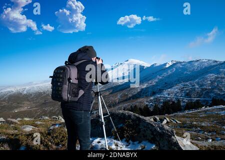 Uomo in montagna fotografando la montagna coperta di neve Foto Stock
