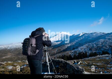 Uomo in montagna fotografando la montagna coperta di neve Foto Stock