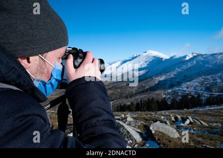 Uomo in montagna fotografando la montagna coperta di neve Foto Stock