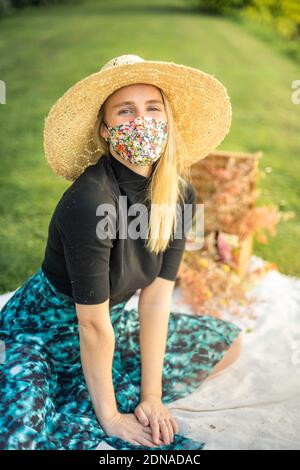 Bella giovane donna sorridente e indossando un elegante maschera di coronavirus elegante copertura per proteggere dalla pandemia Covid-19 Foto Stock