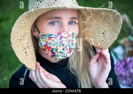 Donna che indossa una maschera elegante che copre come moda per proteggere da Covid-19 durante la pandemia di Coronavirus, mentre ancora aspetto alla moda Foto Stock