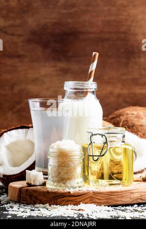 Set di prodotti di cocco: Latte, acqua, olio, trucioli, sfondo scuro, fuoco selettivo Foto Stock