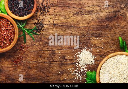 Set quinoa. Grani neri, bianchi e rossi di quinoa cruda in ciotole, groat assortiti, tavola rustica di legno della cucina, vista dall'alto e spazio di copia Foto Stock