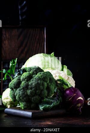 Diversi tipi di cavolo come cavolo bianco, cavolfiore, broccoli, kohlrabi su tavola scura, raccolta autunnale, fuoco selettivo Foto Stock