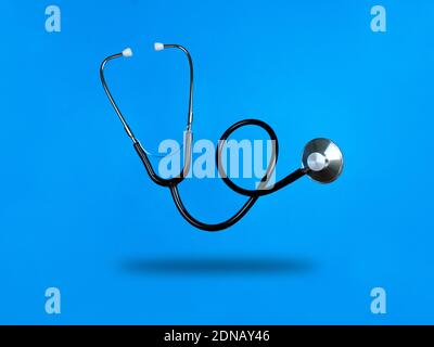 Stetoscopio livitante su sfondo blu e ombra sotto di esso. Foto di scorta. Foto Stock