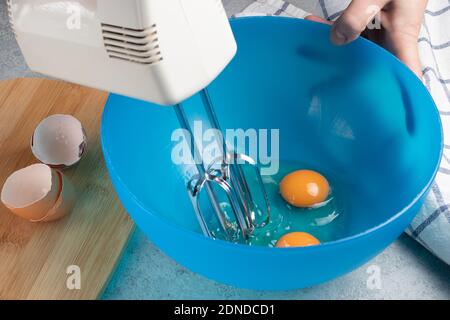 Montare le uova di pollo fresche in un recipiente blu Foto Stock