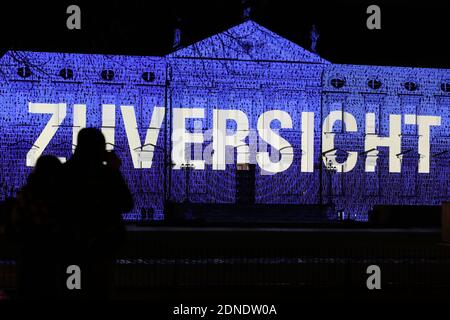 Berlino, Germania. 17 Dicembre 2020. I visitatori potranno ammirare il Palazzo Bellevue illuminato dalla proiezione luminosa della parola "fiducia" in tedesco a Berlino, capitale della Germania, il 17 dicembre 2020. Una leggera proiezione con il tema "Lichtblick (raggio della speranza)" si è tenuta al Bellevue Palace di Berlino, con l'obiettivo di chiedere solidarietà tra il pubblico per combattere la pandemia del COVID-19. Credit: Shan Yuqi/Xinhua/Alamy Live News Foto Stock