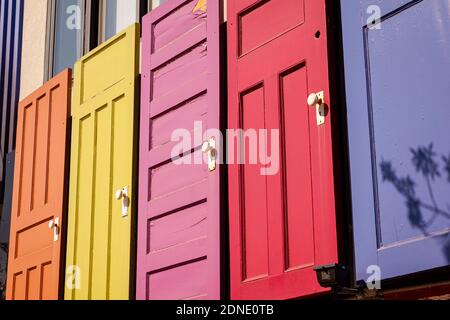 Una fila di vecchie porte a pannelli in legno dipinte di colori luminosi. Foto Stock