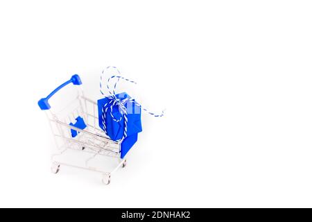 Trolley shopping cart with blue gift box on white background. Copy Space for your text. Stock Photo