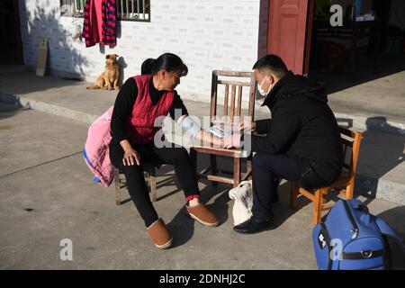 (201218) -- JINZHAI, 18 dicembre 2020 (Xinhua) -- Yu Jiajun visita il suo paziente nella contea di Jinzhai della città di Luan, nella provincia di Anhui della Cina orientale, 16 dicembre 2020. Nel profondo dell'area del bacino idrico di Xianghongdian nella Contea di Jinzhai di Luan City, nella provincia di Anhui, nella Cina orientale, c'è un'isola isolata, che in passato ospita oltre 40 famiglie povere. Yu Jiajun, 42 anni, è l'unico medico del villaggio. 'In passato, non c'era una stazione sanitaria sull'isola. Gli abitanti del villaggio dovevano fare fila per due o tre ore per andare al centro sanitario di Mabu Township per vedere il medico." Yu ha detto. Quando Yu Jiajun tornò alla v Foto Stock