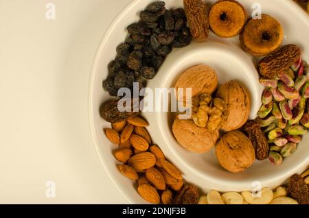 Dried Fruit Almonds, Green Pistachio, Walnut with Shell, Walnut Kernel, dried Fig and dates in white plate . Top angle. Studio Shot Stock Photo