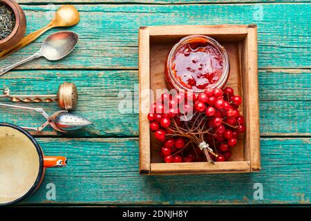 Vasetto con marmellata e viburnum frutti di bosco. Marmellata fatta in casa deliziosa su un tavolo rustico in legno Foto Stock