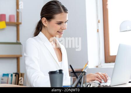 Giovane donna di affari che scrive sul computer portatile che lavora da casa Foto Stock