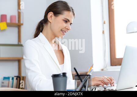 Giovane donna di affari che scrive sul computer portatile che lavora da casa Foto Stock