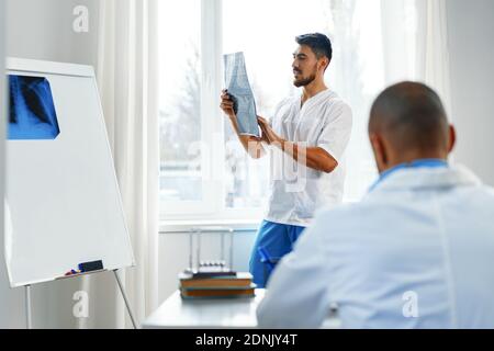 Due medici di sesso maschile esaminano la risonanza magnetica cerebrale di un paziente nel cabinet Foto Stock