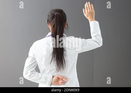 Medico in piedi con le dita incrociate dietro la schiena Foto Stock