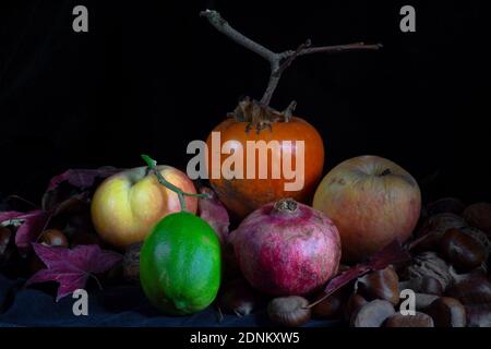 composizione mista di frutta d'autunno e limone verde un piano e uno sfondo scuri Foto Stock