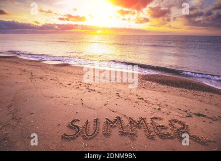 Seascape in the summertime. The word Summer on the beach sand. Inscription Summer on the seashore Stock Photo