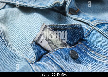 Bolletta da 100 dollari nella tasca della giacca in jeans da primo piano, foto macro