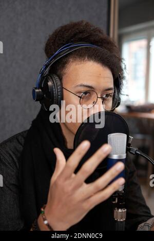 Man wearing headphones and sitting at table with microphone Foto Stock