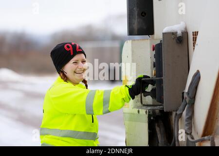 Donna che utilizza un veicolo per la raccolta rifiuti Foto Stock